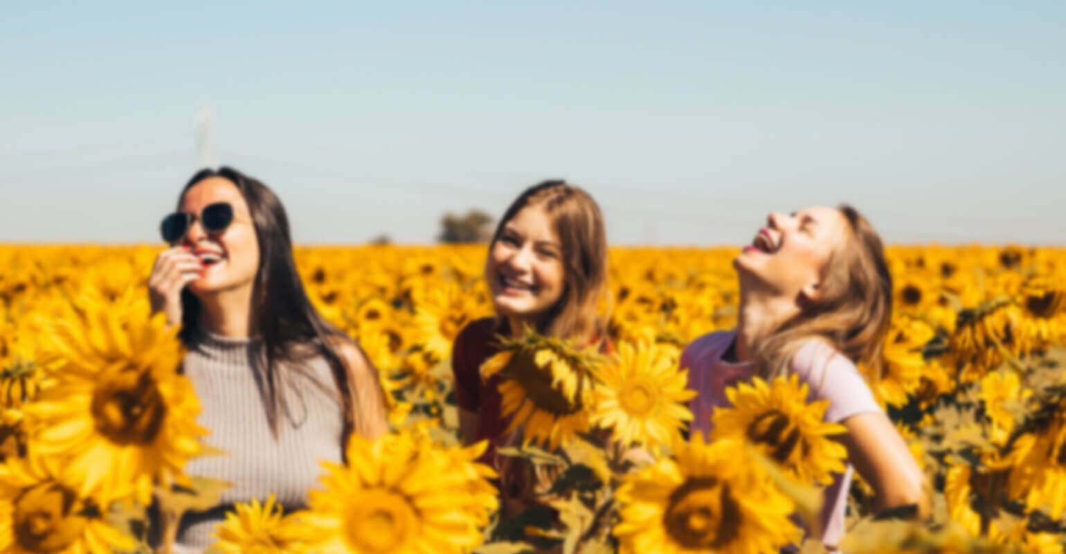 Une petite photo floue de trois femmes debout dans un champ de tournesols.