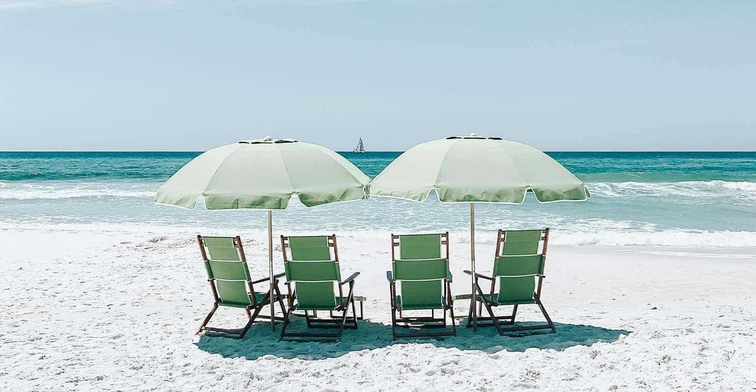 Una foto clara de sillas verdes bajo sombrillas en la arena de la playa